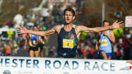 A runner crosses the finish line at the Manchester Road Race, sponsored by ECPC.